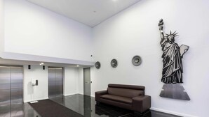 A lobby with a brown sofa, a statue, and three elevators.