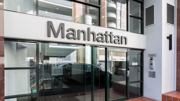 A building with a sign that reads 'Manhattan' and a number '1' indicating its address.