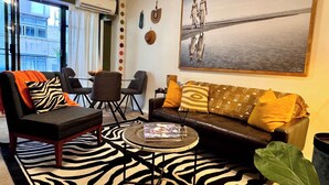 A living room with a zebra-patterned rug, a sofa with patterned cushions, a coffee table, and a painting on the wall.