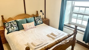 Un lit bien fait, avec une tête de lit en bois, plusieurs oreillers et un ensemble de serviettes.