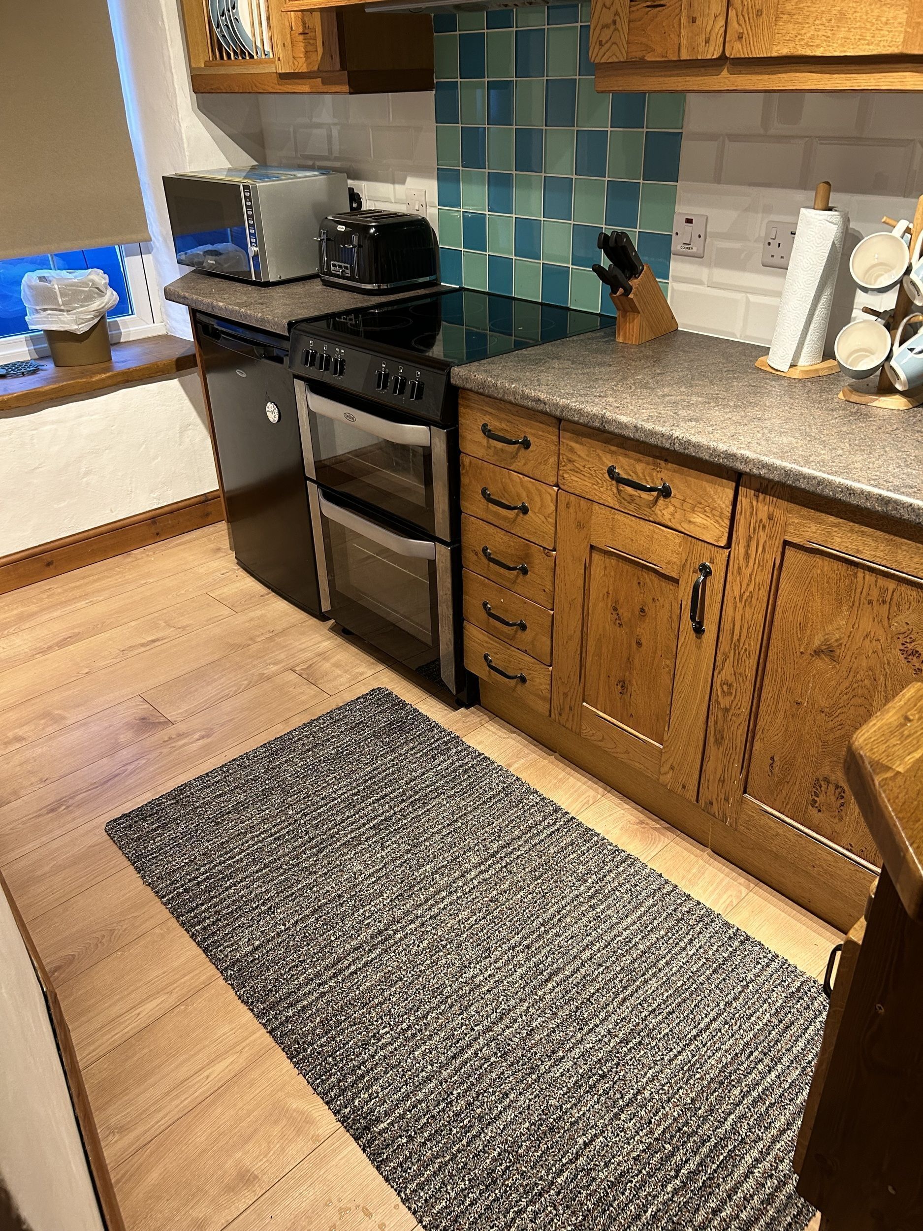 A kitchen with wooden cabinets, a granite countertop, a stove, an oven, and a tiled backsplash.