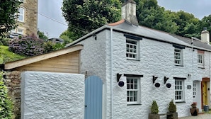 Un bâtiment blanc avec un toit à pignon, une porte bleue et une enseigne indiquant qu’il s’agit d’une maison d’hôtes.