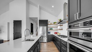 Une cuisine moderne dotée d’un îlot central, d’appareils électroménagers en acier inoxydable et d’un revêtement de sol en bois.