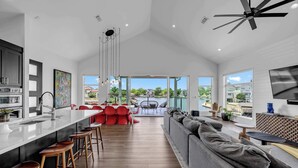 Une cuisine moderne dotée d’un grand îlot central, de tabourets de bar et d’un coin repas avec des chaises rouges.