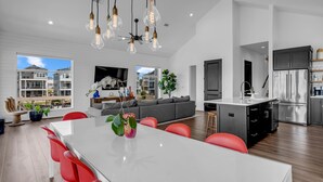 Une cuisine moderne dotée d’un îlot central, d’appareils électroménagers en acier inoxydable et d’un coin repas avec des chaises rouges.