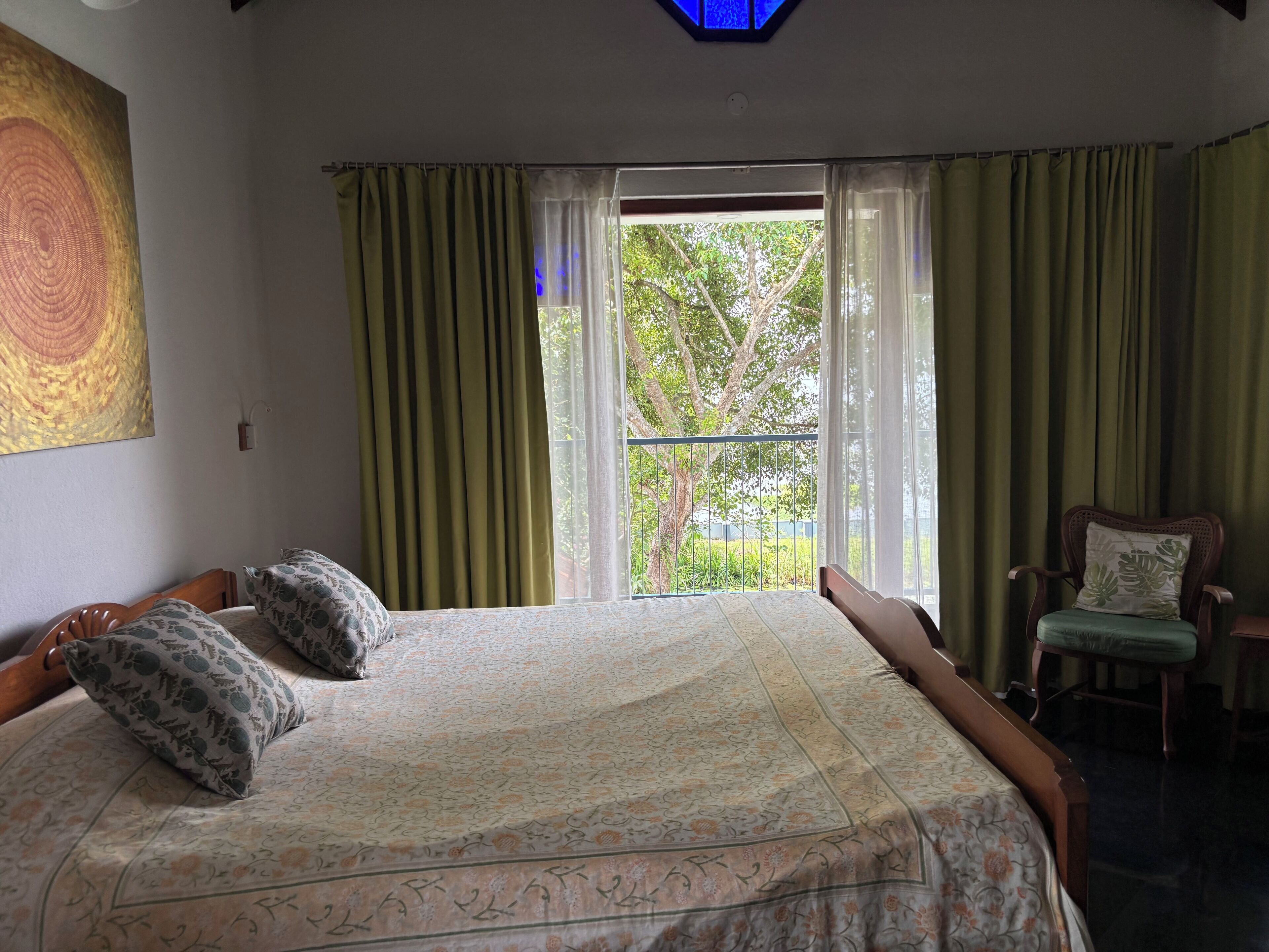 Un dormitorio con una cama, dos almohadas, una silla y una ventana con cortinas.