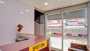 Une salle d'attente avec une enseigne indiquant « Spot On », une plante en pot et une vue sur une rue commerçante.