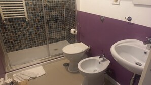 A bathroom with a shower, toilet, bidet, and sink. - Family Suite (Roma)