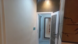 A narrow hallway with white walls, a door with a glass panel, and a sign indicating a staircase. - Family Suite (Roma)