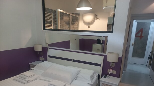 A hotel room with a bed, two bedside tables, a mirror, and a door with the number 4. - Family Suite (Roma)