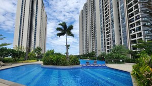 A swimming pool surrounded by greenery and tall residential buildings. - R&F Hotel and Apartment (Phnom Penh)