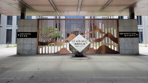 A modern entrance with a metal gate, directional signs for R&F Hotel and R&F Sports Club, and a central sculpture. - R&F Hotel and Apartment (Phnom Penh)