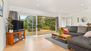 Una sala moderna con un televisor de pantalla plana sobre un mueble de madera, un sofá gris y una mesa de centro de madera.