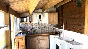 A compact kitchen with wooden cabinets, a microwave, a sink, and a stove. - Seasonal rental Oleron (Saint-Georges-d'Oléron)