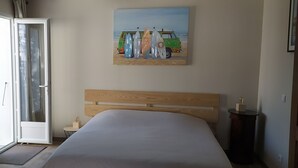 A bedroom with a bed, a painting of surfboards, a wooden headboard, a bedside table, and a nightstand. - Seasonal rental Oleron (Saint-Georges-d'Oléron)