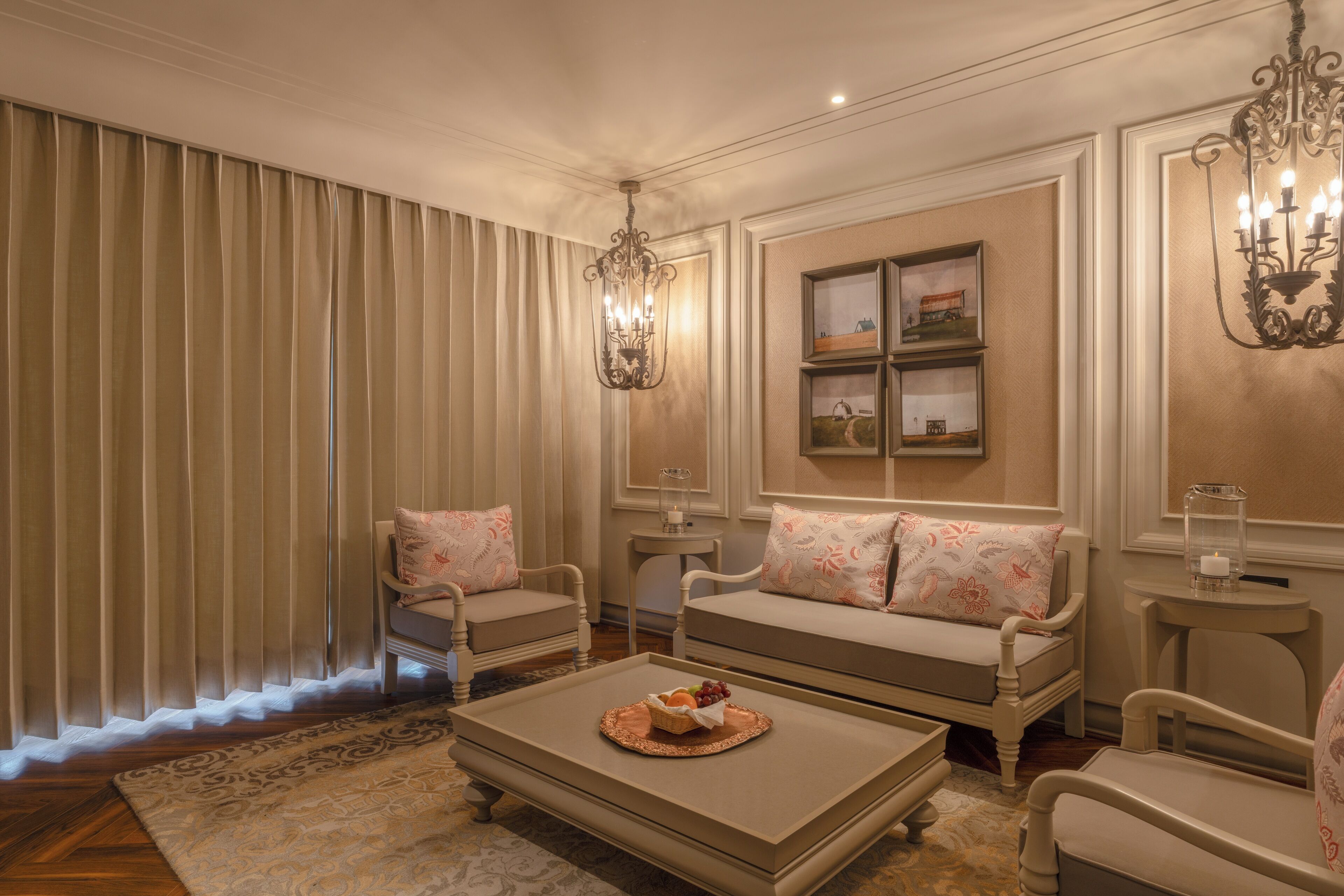 A living room with a sofa set, a coffee table with fruit, and a chandelier.