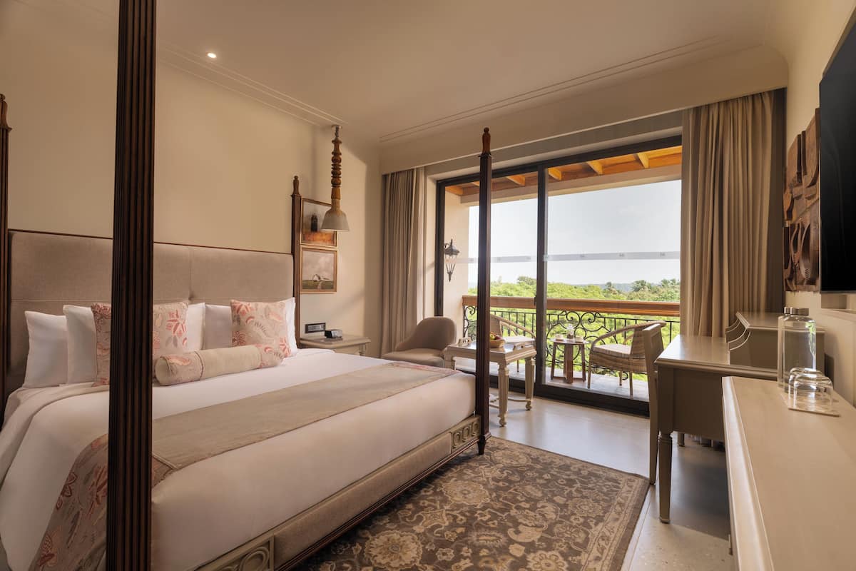 A spacious bedroom with a large bed, a desk, and a balcony with a view.