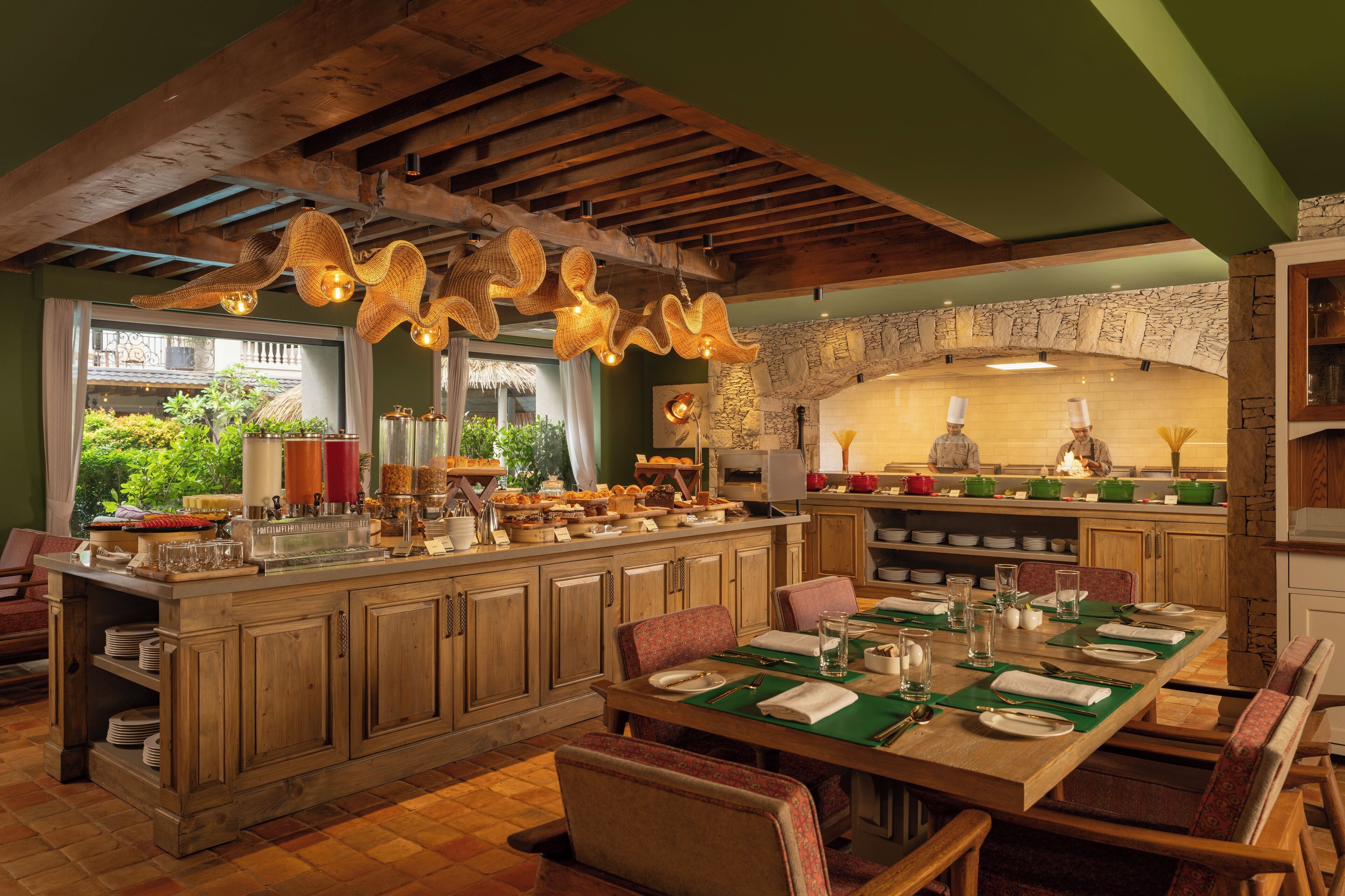 A dining area with a wooden island, green placemats, and a stone archway.