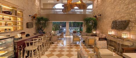 A spacious lobby with a checkered floor, wooden furniture, and a bar area with shelves and a display case.