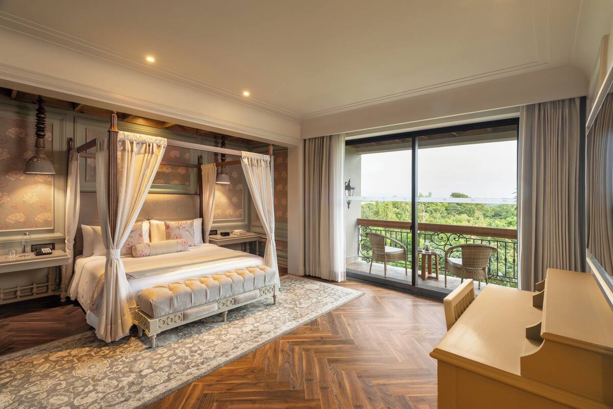 A four-poster canopy bed with a view of a balcony.