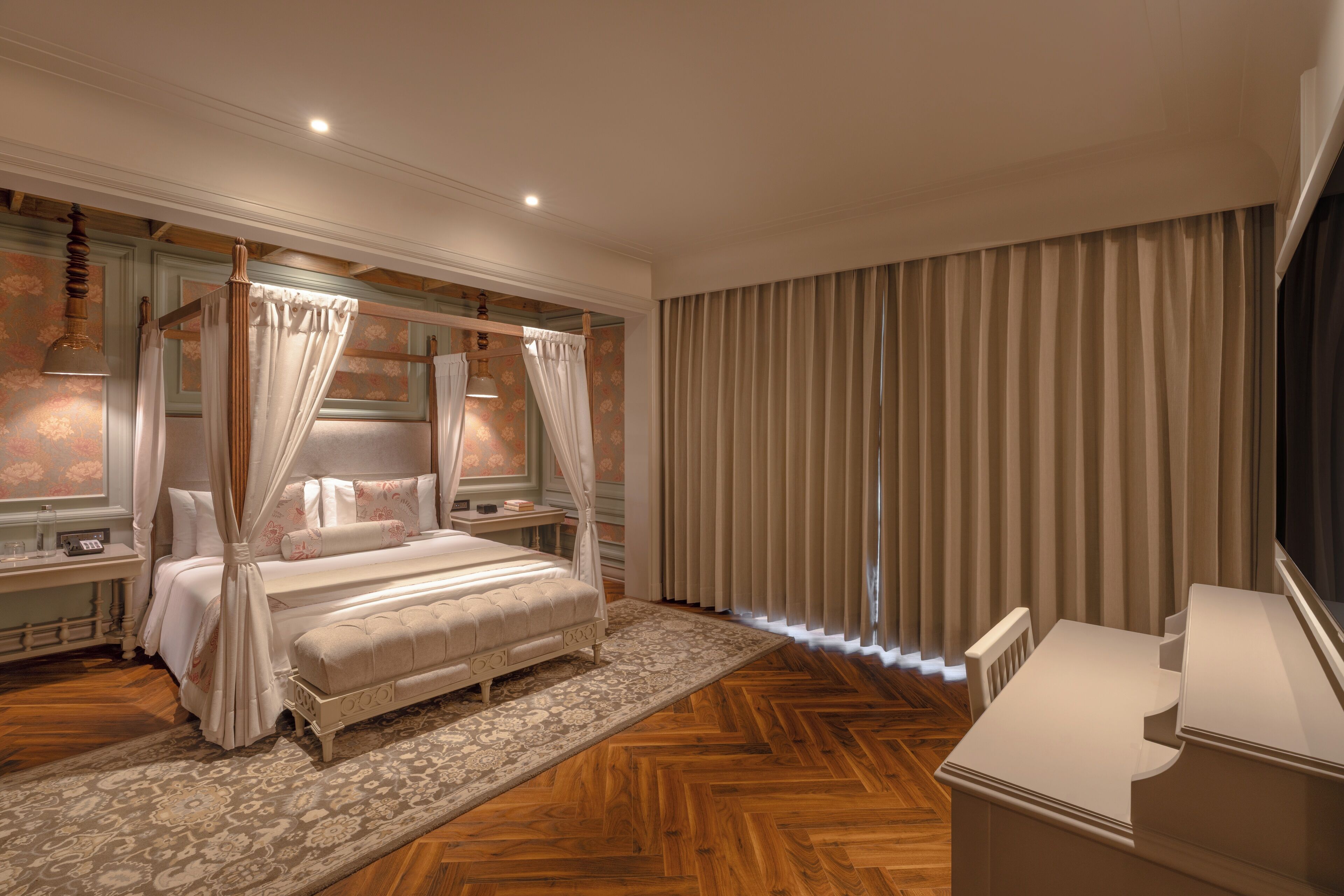 A spacious bedroom with a large bed, a sitting area, and a desk.
