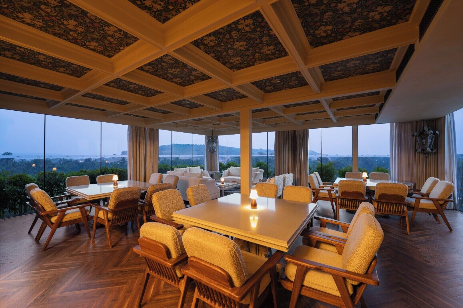 A spacious dining area with high ceilings and large windows offering a view of the landscape.