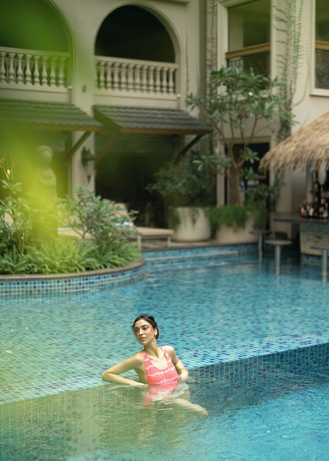 A pool area with a person in a pink swimsuit.