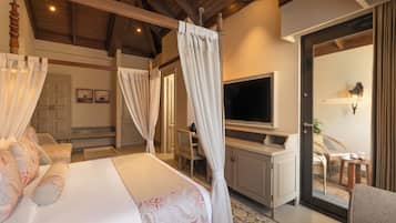 A bedroom with a four-poster bed, a television, and a balcony with wicker furniture.