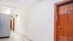 Un pasillo de hotel con una puerta de madera a la derecha, un armario gris a la izquierda y un cartel que indica el número de habitación 201.