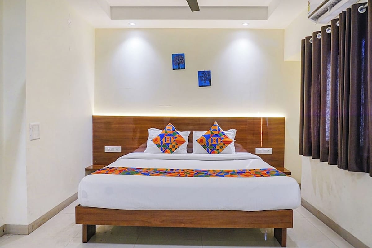 A modern hotel room with a wooden bed, white bedding, and two wall-mounted artworks.