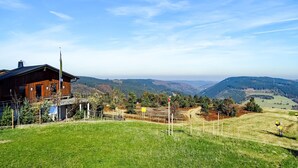 Una cabaña de madera con vistas a colinas ondulantes y un cielo despejado.
