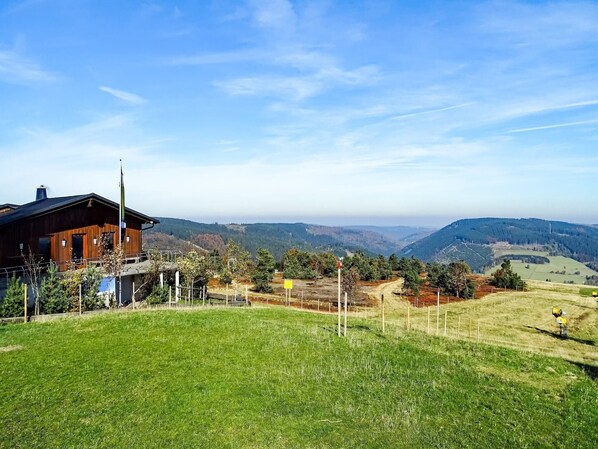 Une cabane en bois offrant une vue sur des collines verdoyantes et un ciel dégagé.