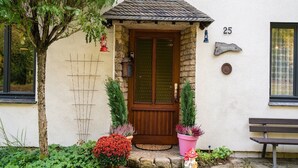 Una casa con puerta de madera, pared de piedra y el número 25 sobre la puerta.