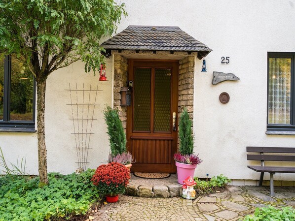 Une maison avec une porte en bois, un mur en pierre et le numéro « 25 » au-dessus de la porte.