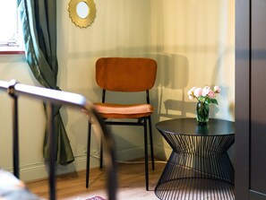 Une pièce comprenant une chaise, une petite table ronde et un vase avec des fleurs.