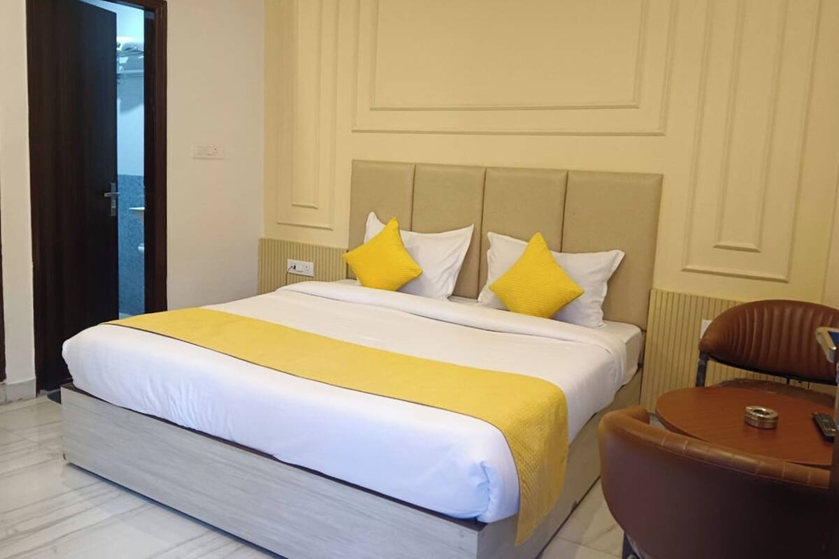 Een hotelkamer met een groot bed, een bruine leren fauteuil en een kleine tafel.