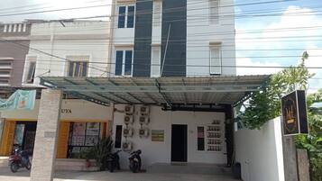 A building with a covered entrance, air conditioning units, and a sign for 'UYA'.