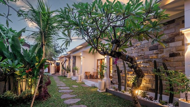 Ein modernes Haus mit einer Natursteinfassade, einem Kiesweg und üppiger Bepflanzung.