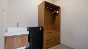 Ein kleines Badezimmer mit Waschbecken, einem schwarzen Kühlschrank und einem Holzschrank.