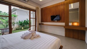 Ein Hotelzimmer mit einem Bett, einem an einer Holzpaneelenwand montierten Fernseher und Blick auf den Garten durch eine Schiebetür.