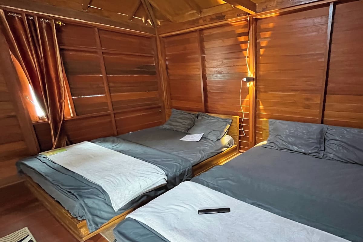 A cabin with two wooden beds, each with a pillow and a blanket.
