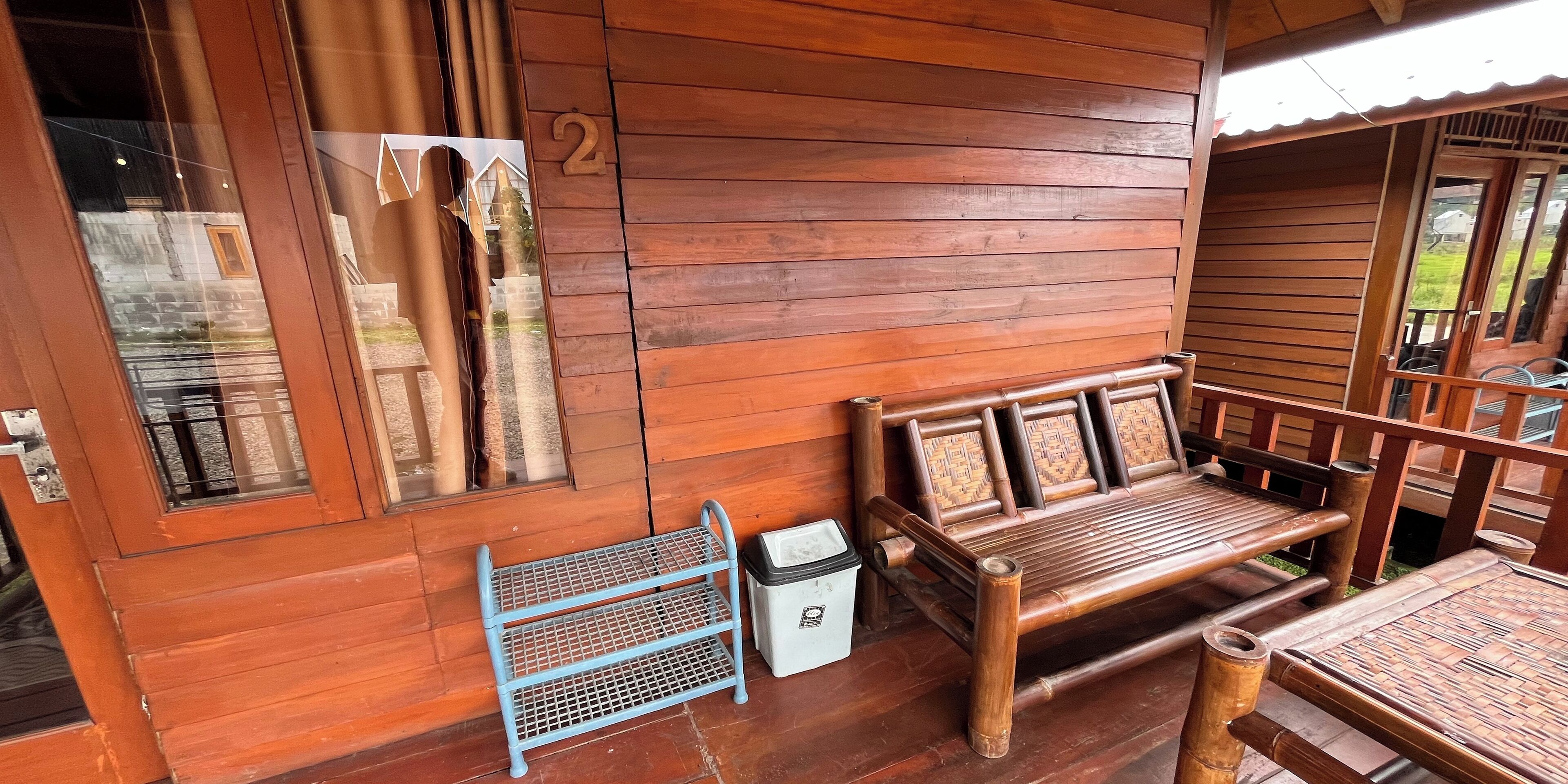 A wooden cabin with a bench and a metal rack.