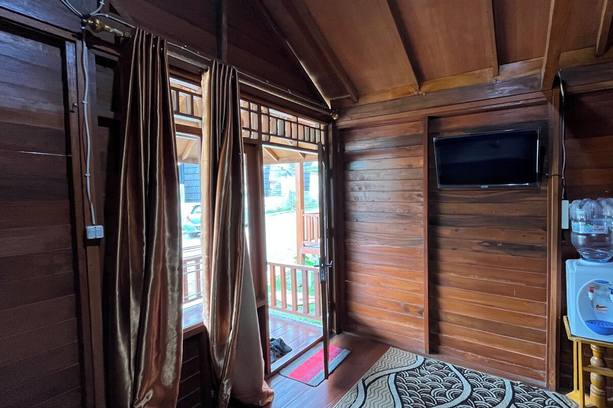 A wooden interior with a sliding door, a water dispenser, and a television mounted on the wall.