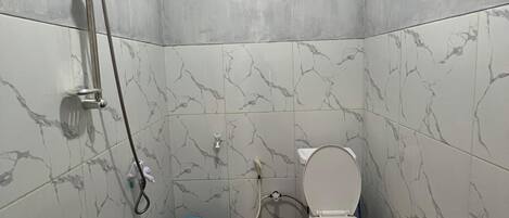 A bathroom with a toilet, a shower, and a window.