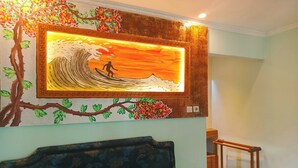 A bedroom with a bed, a wall-mounted artwork depicting a surfer, and a staircase.