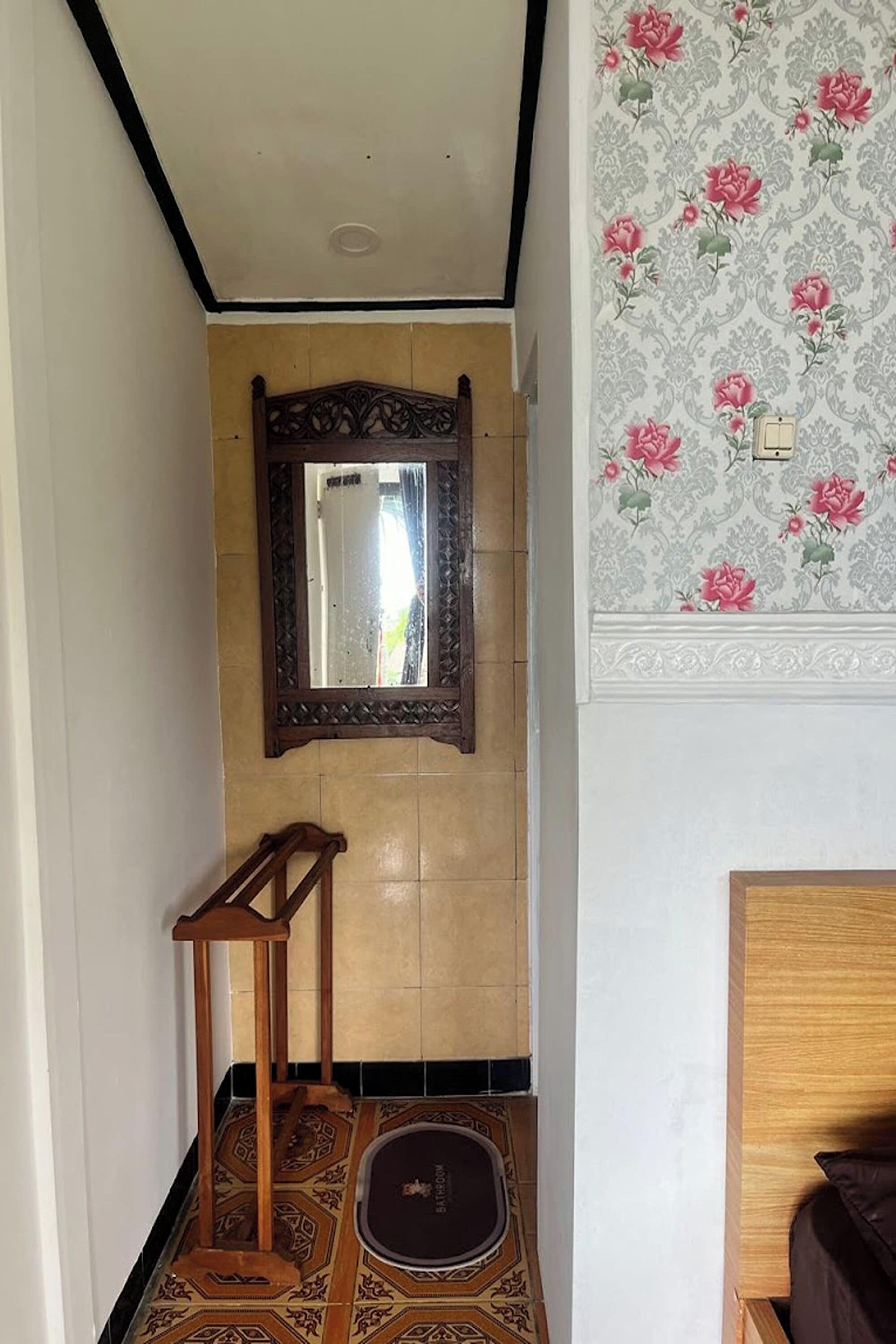 Een badkamer met een houten vloer, een spiegel en een behang met een patroon.