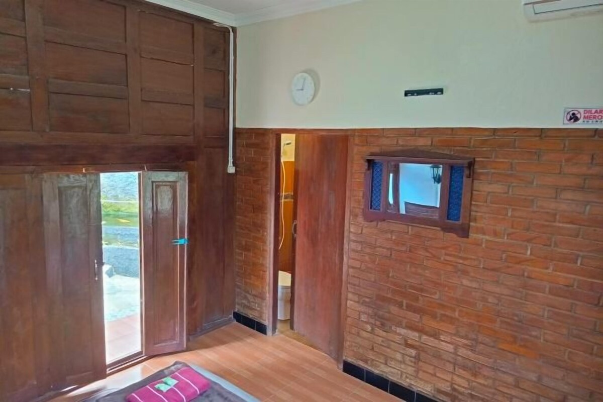 A room with a wooden door, a small window, and a brick wall.