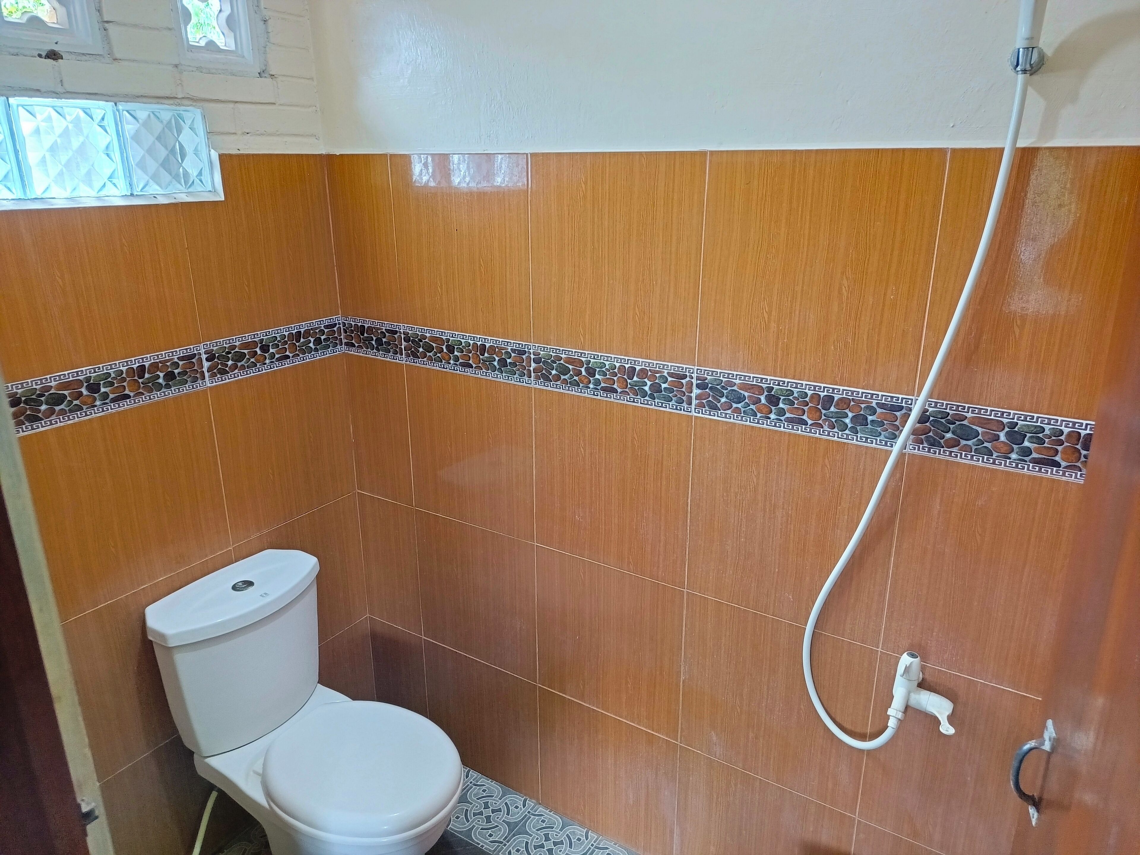 A small bathroom with a toilet, a shower, and a tiled floor.