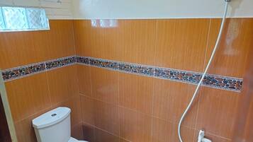 Een kleine badkamer met toilet, douche en betegelde vloer.