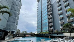 A modern hotel with a swimming pool and lounge chairs.